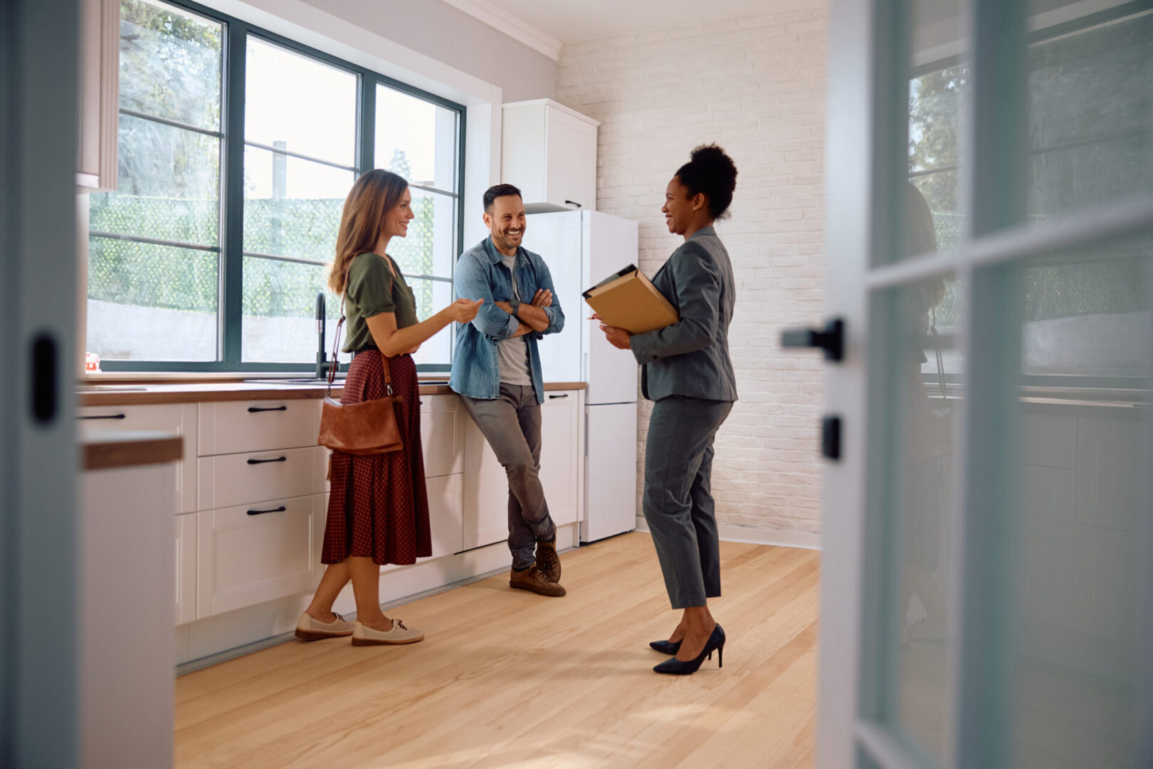 Three people having a discussion in a modern kitchen.